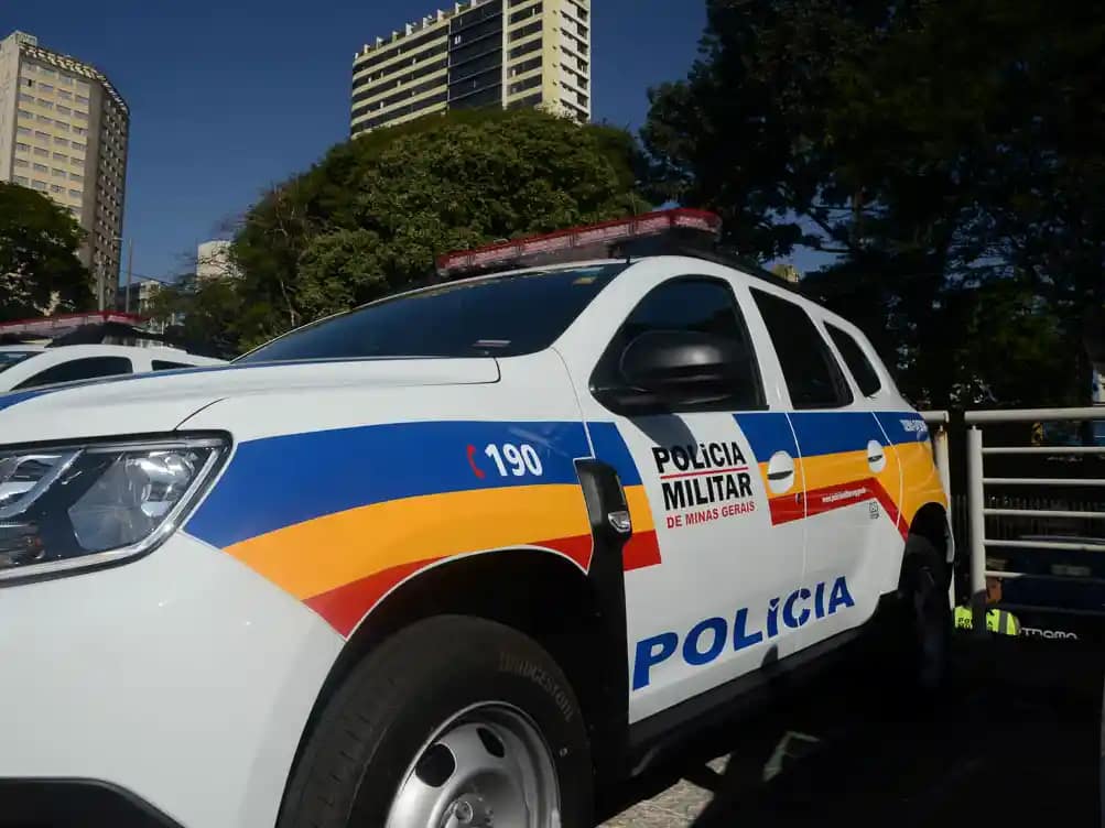 Carro de cor branca com adesivos da Polícia Militar.
