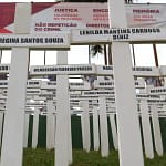 Imagem mostra um memorial composto por dezenas de cruzes brancas fincadas no chão, cada uma com o nome de uma das vítimas da tragédia de Brumadinho.