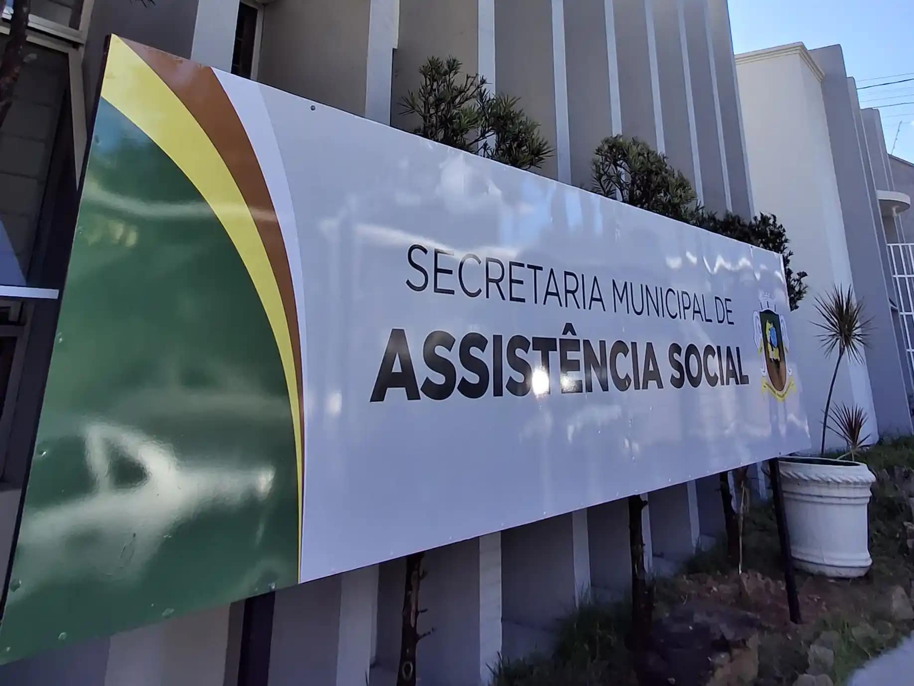 A imagem mostra a fachada de um prédio público, onde se destaca uma placa institucional com os dizeres “Secretaria Municipal de Assistência Social”.
