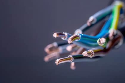 A imagem apresenta cabos elétricos desencapados, evidenciando os condutores de cobre expostos nas extremidades. Os fios possuem revestimentos isolantes coloridos, em tons como azul, verde, amarelo e preto, padrão comum em instalações elétricas.